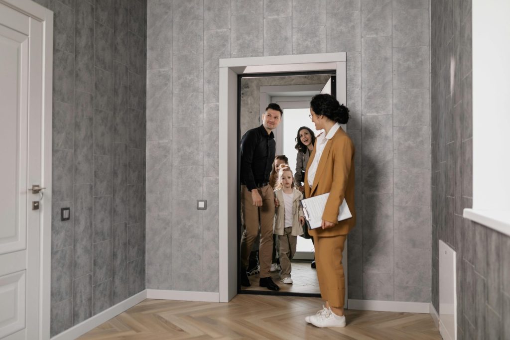 Eine Familie erkundet mit einem Immobilienmakler ein neues Zuhause in einem modernen Interieur.